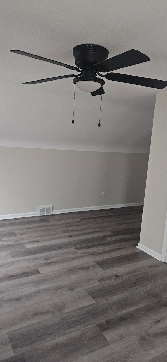 empty room with ceiling fan, vaulted ceiling, wood finished floors, and visible vents