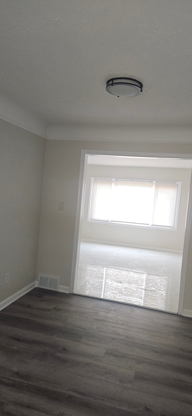 unfurnished room with ornamental molding, visible vents, baseboards, and wood finished floors