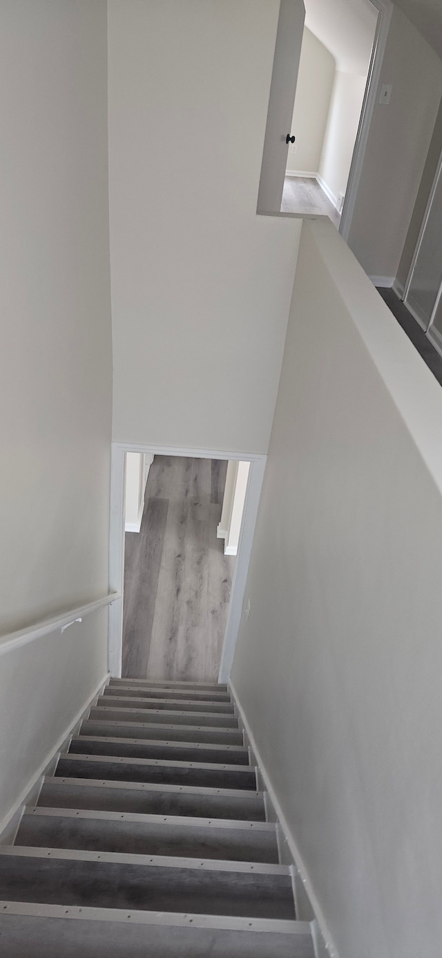 staircase with baseboards and wood finished floors