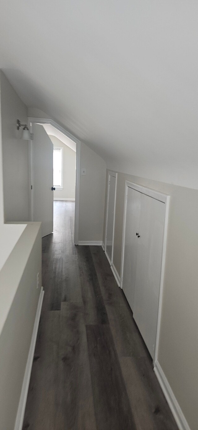 hall with lofted ceiling, dark wood-type flooring, and baseboards