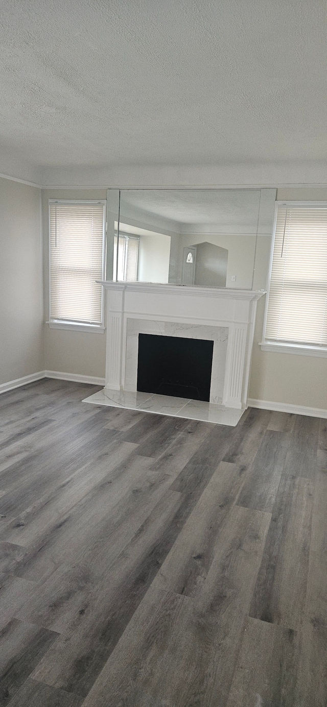 unfurnished living room with a high end fireplace, baseboards, and wood finished floors