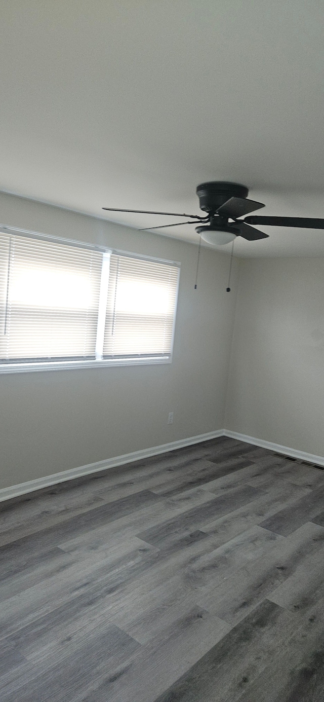 empty room with ceiling fan, baseboards, and wood finished floors