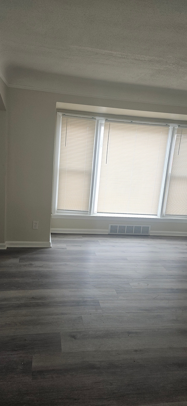 unfurnished room with baseboards, a textured ceiling, visible vents, and dark wood-type flooring