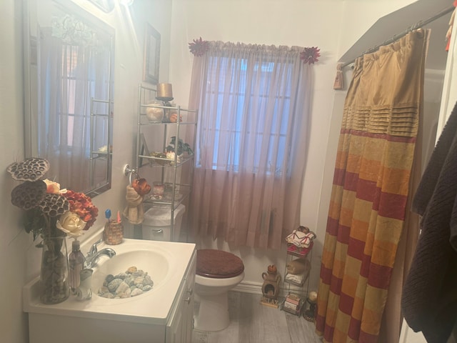 bathroom with hardwood / wood-style floors, vanity, a shower with shower curtain, and toilet