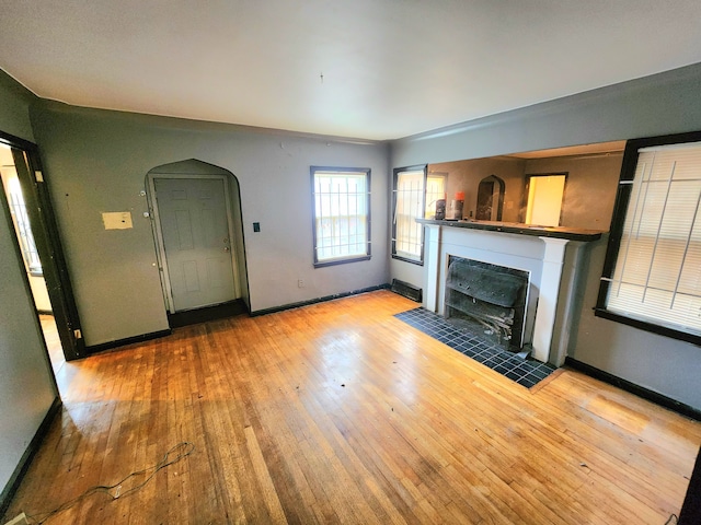 unfurnished living room with light wood-type flooring and a tiled fireplace