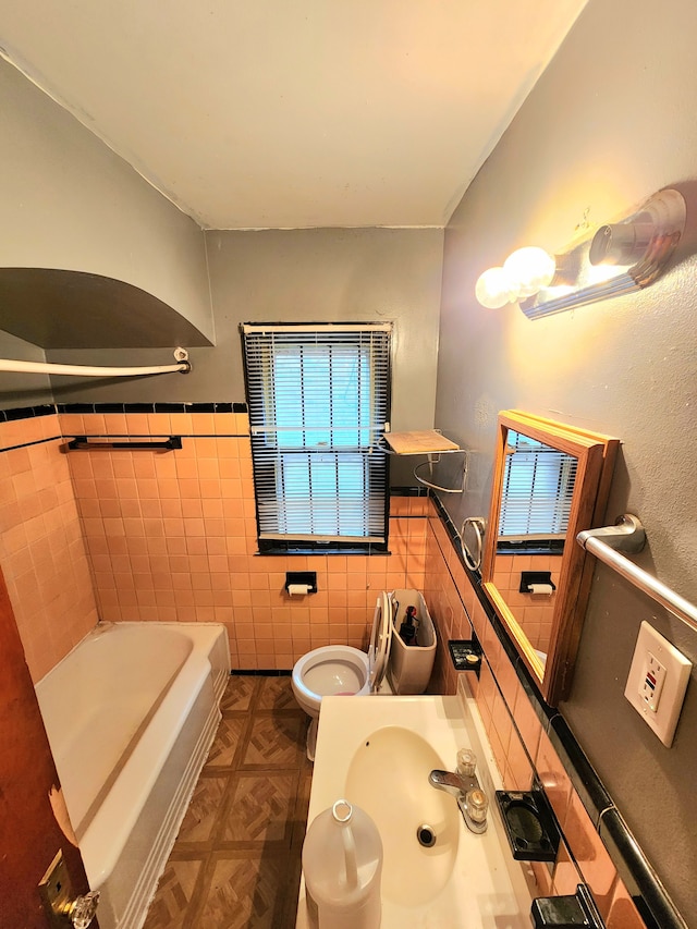 bathroom with a bathtub, toilet, tile walls, and sink