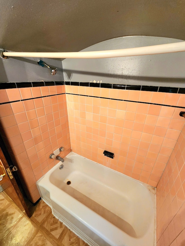 bathroom with tiled shower / bath combo and tile walls