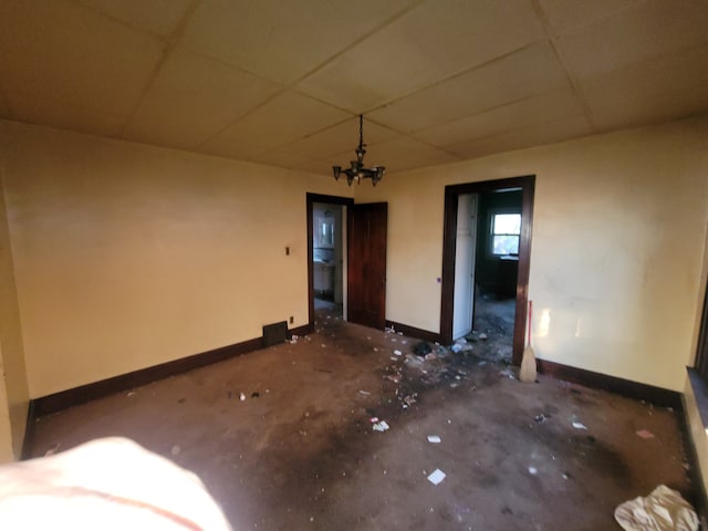 unfurnished room with a paneled ceiling and a chandelier