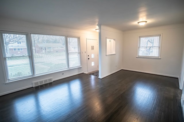 unfurnished room featuring dark wood-style floors, visible vents, and baseboards