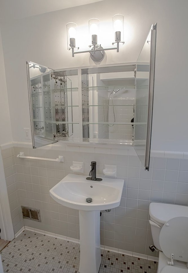 bathroom featuring toilet, tile patterned floors, and tile walls