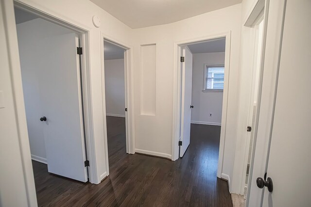 corridor with baseboards and dark wood finished floors