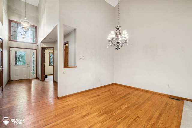 foyer entrance with hardwood / wood-style floors, a high ceiling, and an inviting chandelier