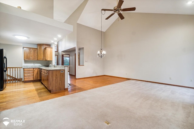 kitchen featuring pendant lighting, ceiling fan with notable chandelier, fridge, light hardwood / wood-style floors, and kitchen peninsula