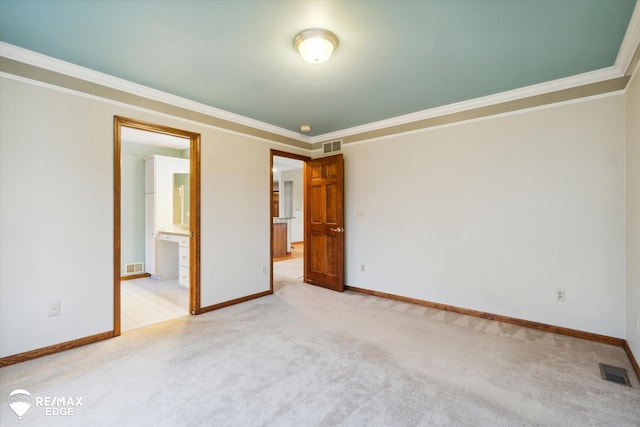 unfurnished bedroom featuring crown molding, light carpet, and ensuite bath