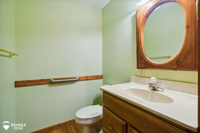 bathroom with wood-type flooring, vanity, and toilet