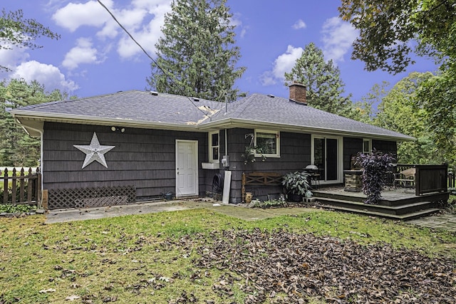 rear view of house featuring a wooden deck and a yard