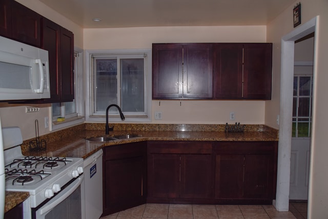 kitchen with white appliances, light tile patterned floors, sink, and dark stone countertops