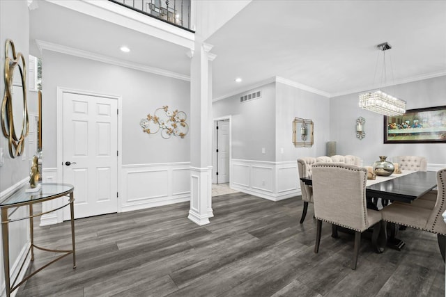 dining room with ornate columns, a notable chandelier, dark wood-type flooring, and crown molding