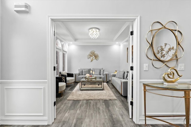 living room with hardwood / wood-style floors, a raised ceiling, and crown molding