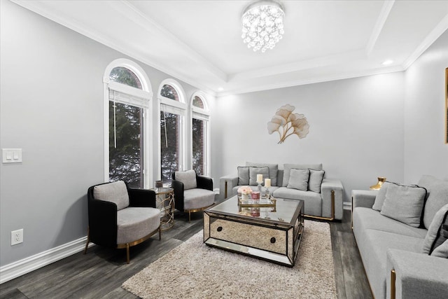 living room featuring an inviting chandelier, a raised ceiling, dark wood-type flooring, and crown molding