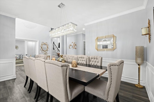 dining area with a notable chandelier, ornamental molding, and dark wood-type flooring