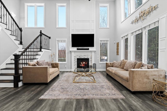 living room with a tiled fireplace, a towering ceiling, and dark hardwood / wood-style floors