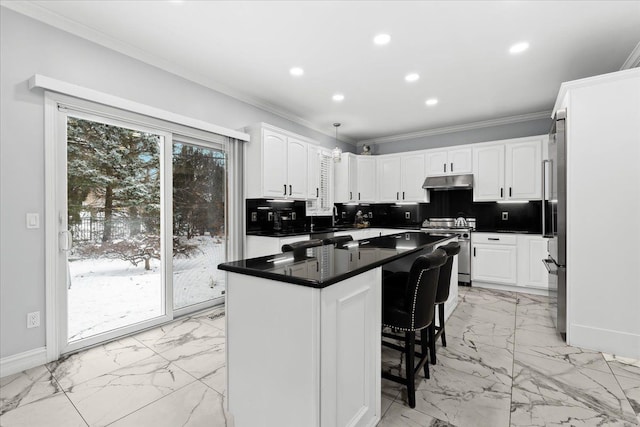 kitchen with white cabinets, stainless steel stove, hanging light fixtures, and a kitchen island