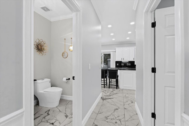 bathroom with decorative backsplash, toilet, and ornamental molding