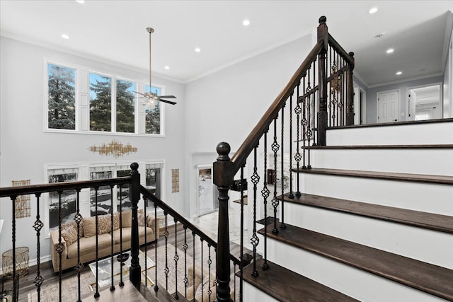 stairs featuring wood-type flooring, ceiling fan, and crown molding