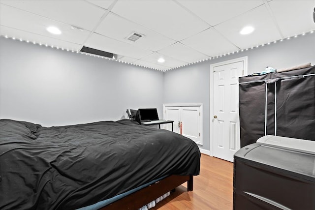 bedroom featuring light wood-type flooring and a paneled ceiling