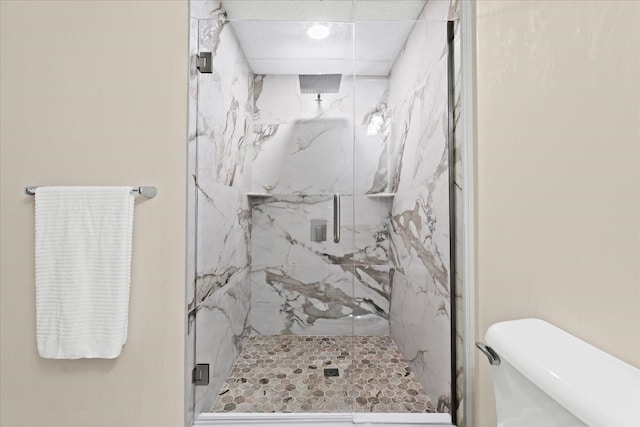 bathroom featuring a shower with shower door and toilet