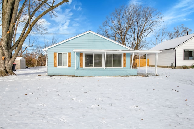 snow covered rear of property with a shed