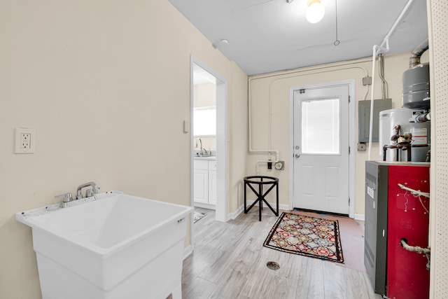 foyer with water heater, sink, electric panel, and light hardwood / wood-style flooring