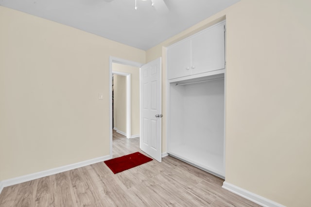 unfurnished bedroom with ceiling fan, light wood-type flooring, and a closet