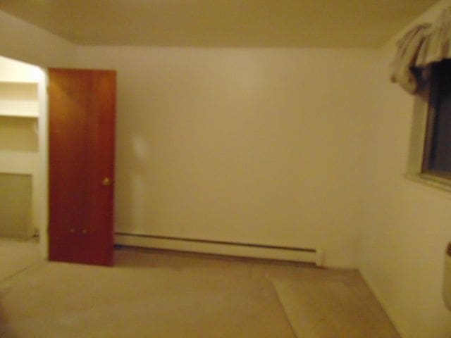 unfurnished bedroom featuring a baseboard heating unit