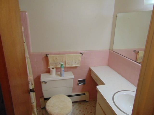 bathroom featuring tile patterned floors, vanity, a baseboard heating unit, tile walls, and toilet