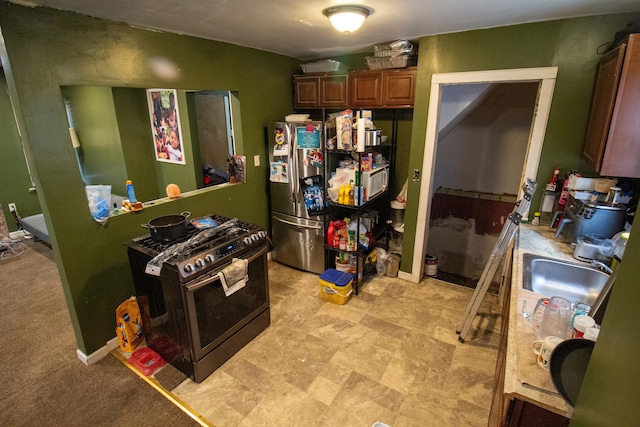 kitchen featuring black gas range, stainless steel fridge, and sink