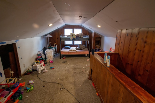 bedroom featuring light colored carpet, vaulted ceiling, and wooden walls