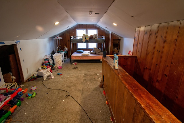 carpeted bedroom with vaulted ceiling and wood walls