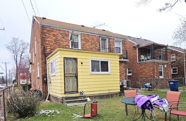 rear view of property with a lawn and a balcony