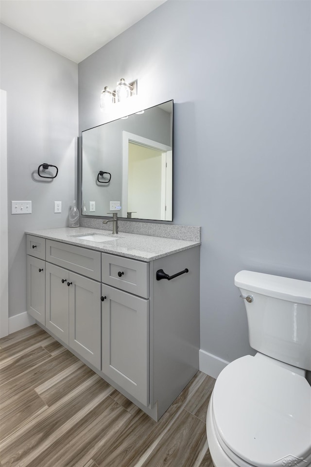 bathroom with vanity, toilet, and wood-type flooring