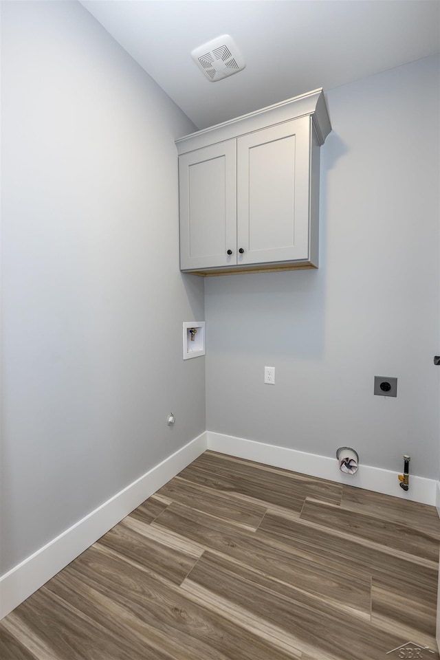 clothes washing area with hookup for an electric dryer, hookup for a washing machine, cabinets, gas dryer hookup, and dark hardwood / wood-style floors