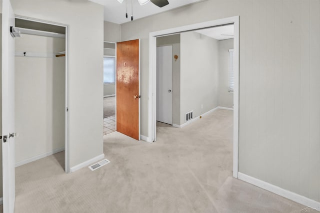 unfurnished bedroom with ceiling fan, light colored carpet, and a closet