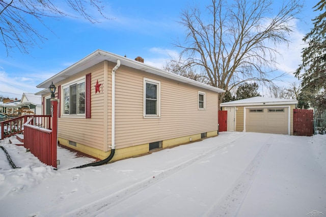 view of snow covered exterior featuring a garage and an outbuilding