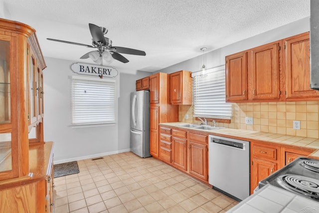 kitchen with stainless steel appliances, ceiling fan, tile countertops, and decorative backsplash