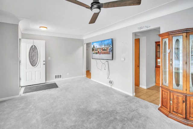 foyer entrance featuring ceiling fan and light carpet