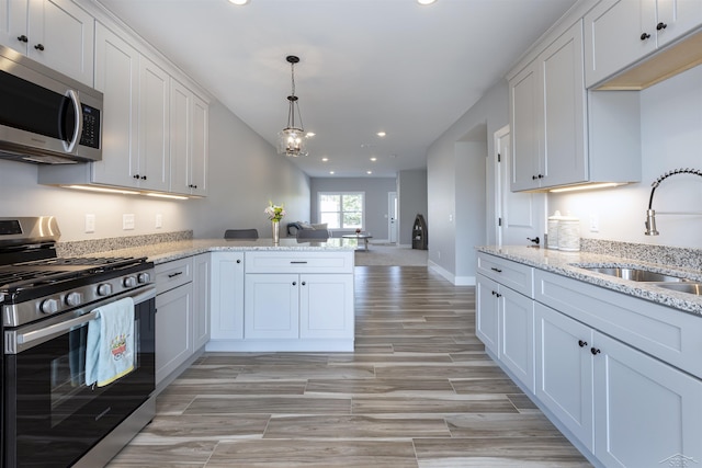 kitchen with white cabinets, stainless steel appliances, light stone countertops, and sink