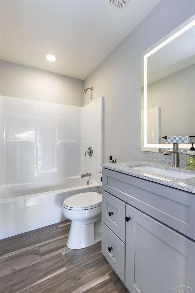 full bathroom featuring vanity, hardwood / wood-style floors, washtub / shower combination, and toilet