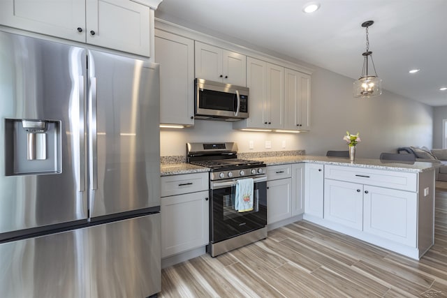 kitchen with white cabinetry, hanging light fixtures, light stone counters, appliances with stainless steel finishes, and light wood-type flooring