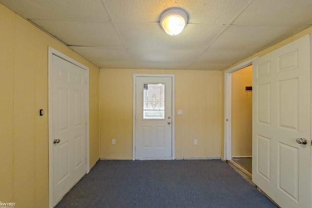 interior space featuring a paneled ceiling and dark carpet